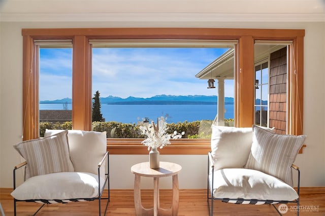 living area featuring a healthy amount of sunlight, crown molding, and wood finished floors