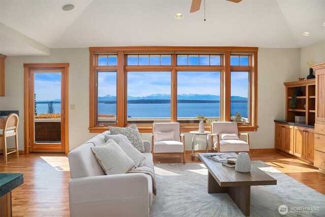 living room with light wood-style floors, a water and mountain view, a ceiling fan, and lofted ceiling