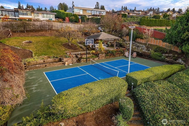 view of basketball court featuring basketball court, a tennis court, fence, a gazebo, and a residential view