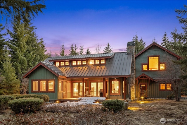 121 Hard Scrabble Ln, Cle Elum, WA 98922 - back of house at dusk with board and batten siding, a chimney, a standing seam roof, a porch, and metal roof