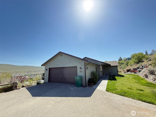 ranch-style house with a garage, aphalt driveway, and a front yard