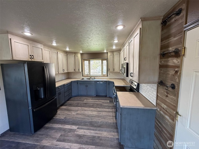 kitchen with a sink, a textured ceiling, appliances with stainless steel finishes, and blue cabinets