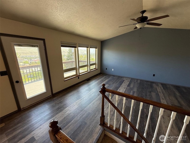 unfurnished room featuring a textured ceiling, dark wood finished floors, a ceiling fan, and lofted ceiling
