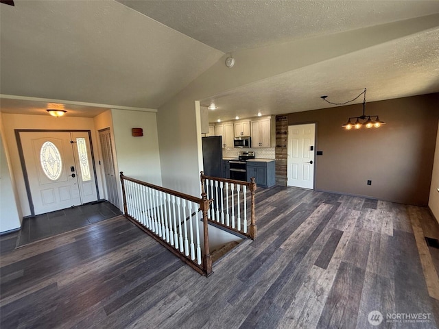 entryway with dark wood finished floors, a textured ceiling, and lofted ceiling