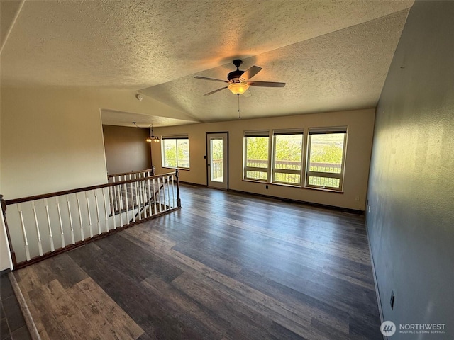 empty room featuring a textured ceiling, lofted ceiling, wood finished floors, and ceiling fan with notable chandelier