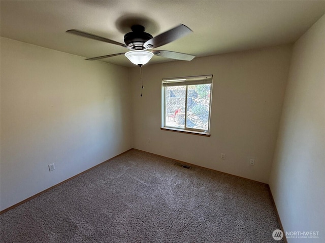 carpeted spare room featuring visible vents and ceiling fan