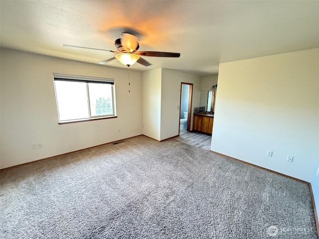 empty room featuring light colored carpet, baseboards, ceiling fan, and visible vents