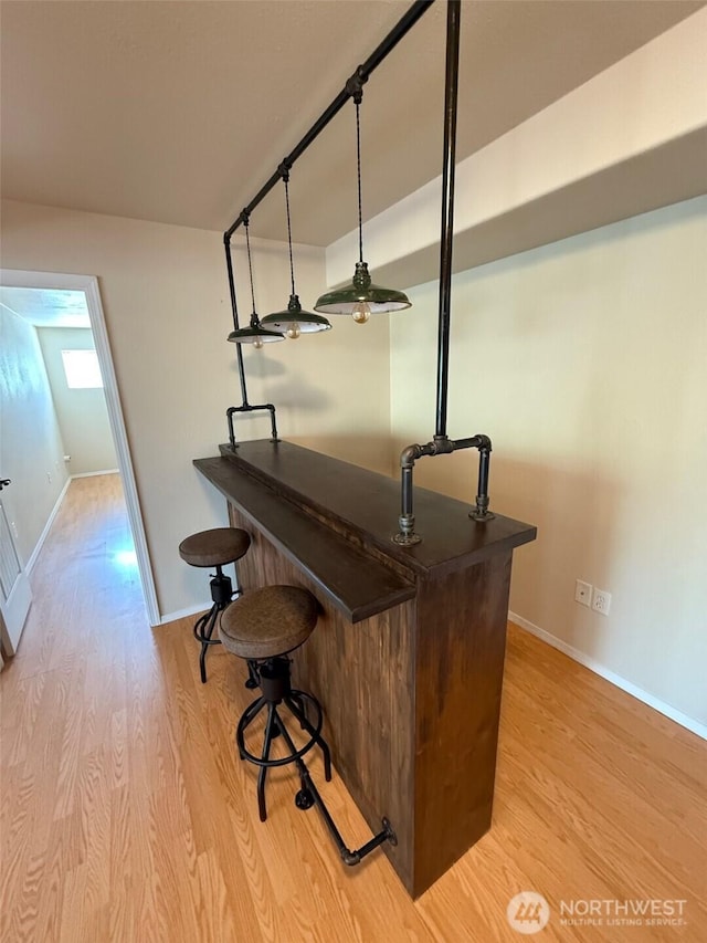 bar featuring baseboards and light wood-style flooring