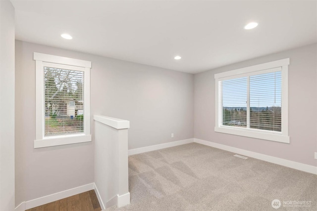 carpeted spare room with baseboards, visible vents, recessed lighting, and a wealth of natural light