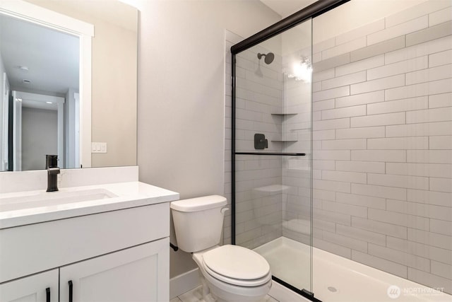 full bath with vanity, baseboards, a shower stall, and toilet