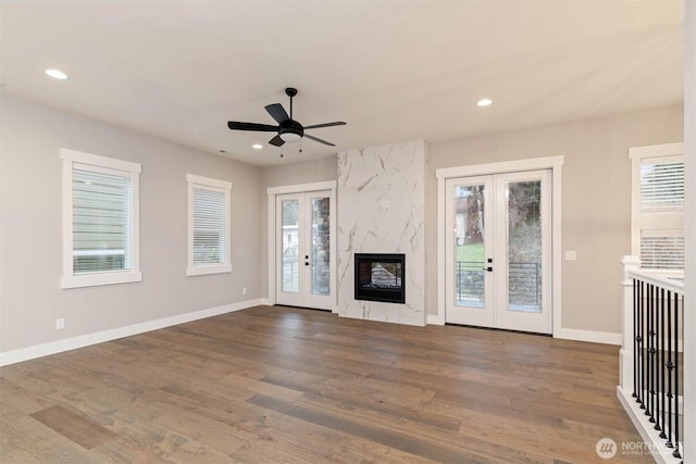 unfurnished living room with a healthy amount of sunlight, a ceiling fan, french doors, and wood finished floors