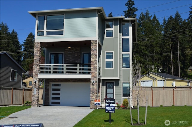 contemporary house featuring fence, a balcony, a front yard, stone siding, and concrete driveway