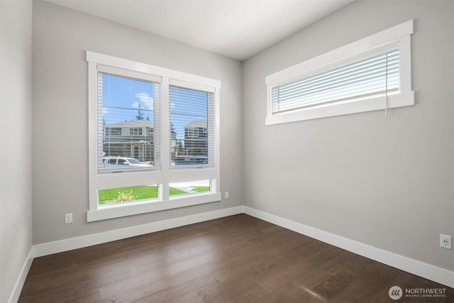 empty room with dark wood-style flooring and baseboards