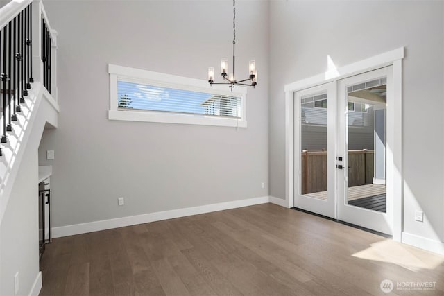 unfurnished dining area with french doors, baseboards, a chandelier, stairs, and dark wood-type flooring
