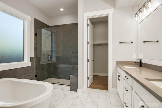 full bathroom with double vanity, a freestanding bath, a stall shower, a sink, and baseboards