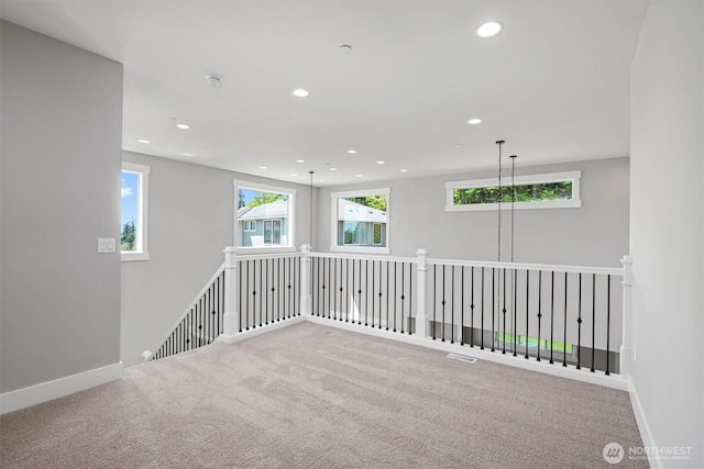 carpeted spare room featuring a healthy amount of sunlight, baseboards, and recessed lighting