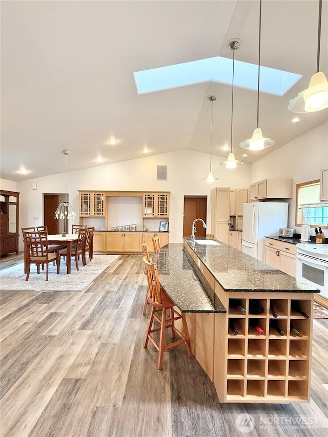 kitchen with a sink, lofted ceiling with skylight, light wood-type flooring, and white appliances