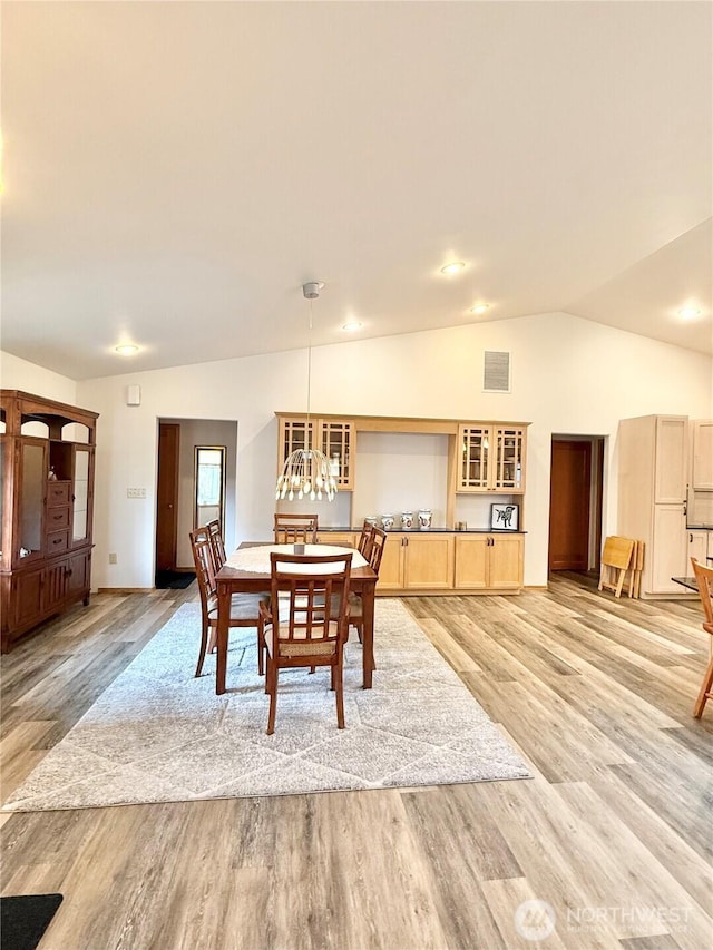dining area featuring visible vents, an inviting chandelier, light wood-style flooring, and vaulted ceiling
