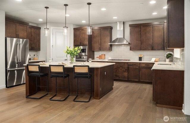 1497 Elk Run Pl SE, North Bend, WA 98045 - kitchen featuring appliances with stainless steel finishes, wall chimney exhaust hood, wood finished floors, a sink, and recessed lighting