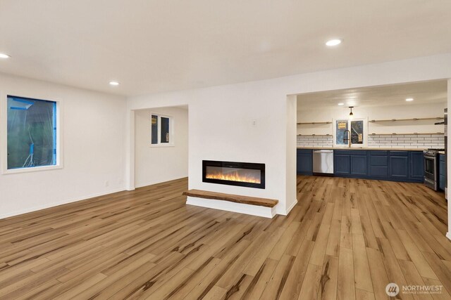 13574 S Green St, Anacortes, WA 98221 - unfurnished living room featuring a glass covered fireplace, recessed lighting, light wood-style floors, and a sink