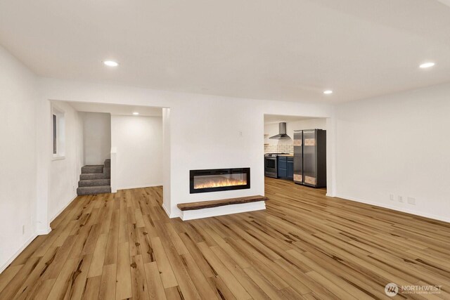 13574 S Green St, Anacortes, WA 98221 - unfurnished living room with a glass covered fireplace, recessed lighting, stairway, and light wood-style floors
