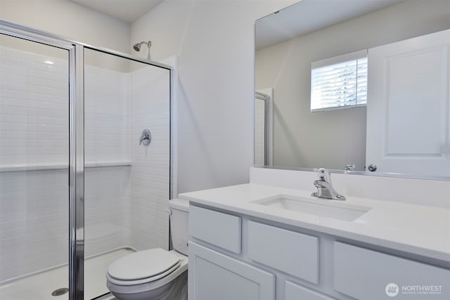 full bath with a stall shower, toilet, and vanity
