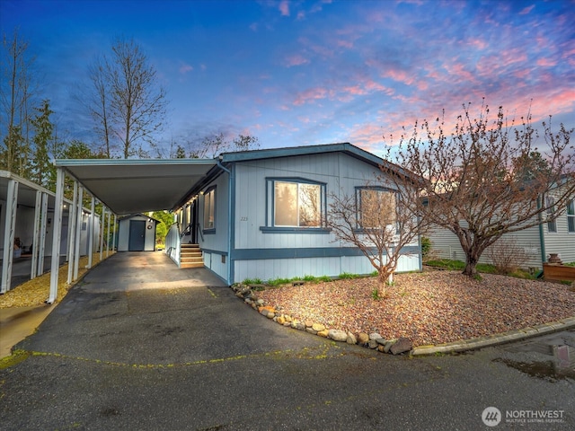 view of front of property featuring an outdoor structure, aphalt driveway, an attached carport, and a storage unit
