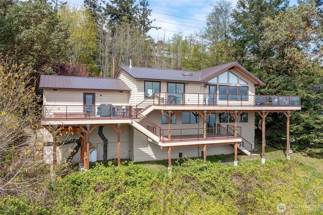 rear view of house with stairway, a deck, a sunroom, and metal roof