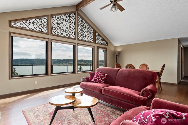 living area with baseboards, beamed ceiling, a ceiling fan, wood finished floors, and high vaulted ceiling