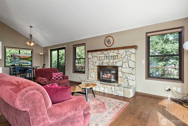 living area with wood finished floors, baseboards, a fireplace, and vaulted ceiling