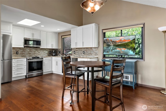 kitchen featuring white cabinets, appliances with stainless steel finishes, tasteful backsplash, and dark wood-type flooring