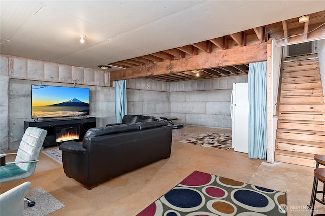 unfinished below grade area featuring a glass covered fireplace, freestanding refrigerator, and stairs
