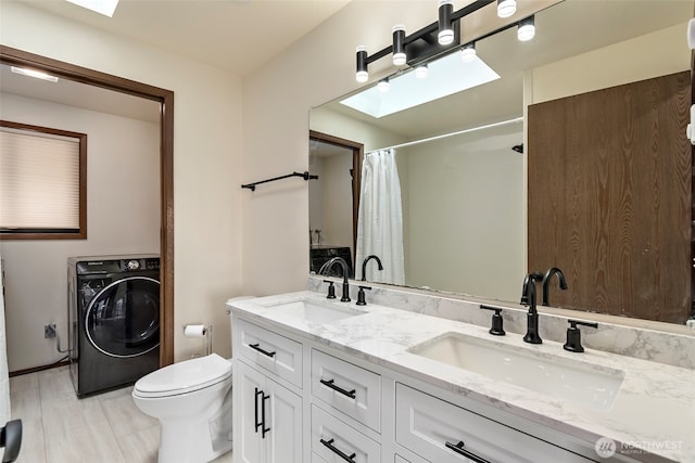 bathroom featuring washer / dryer, a skylight, and a sink