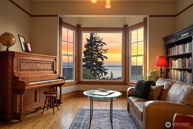 sitting room with a water view, baseboards, and wood finished floors