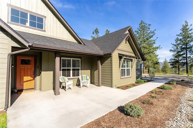 rear view of property with a patio, board and batten siding, and roof with shingles