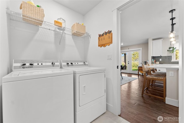clothes washing area featuring laundry area, french doors, washing machine and clothes dryer, baseboards, and light wood-style flooring