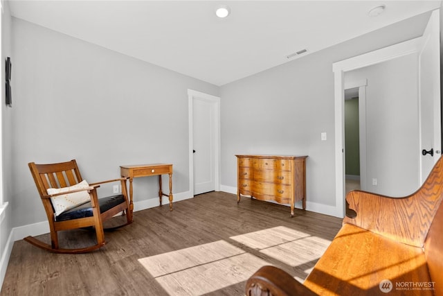 sitting room with baseboards, visible vents, and wood finished floors
