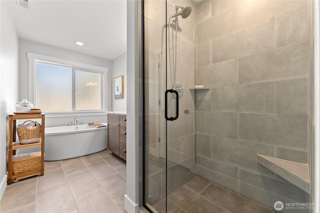 bathroom with a freestanding bath, vanity, a stall shower, and tile patterned floors