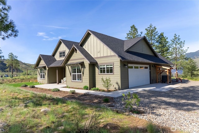 craftsman inspired home with board and batten siding, roof with shingles, a garage, a mountain view, and gravel driveway