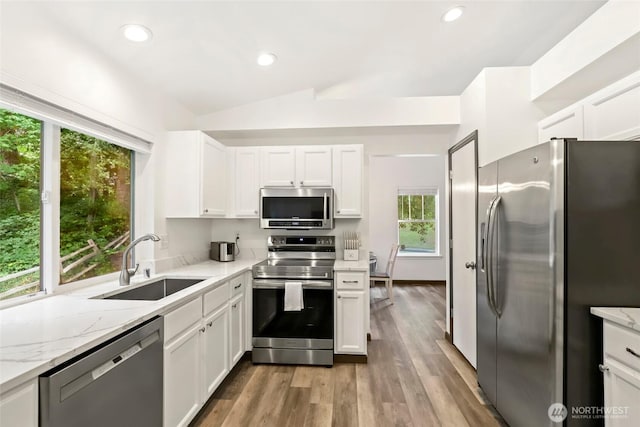 kitchen featuring vaulted ceiling, white cabinets, a sink, and stainless steel appliances