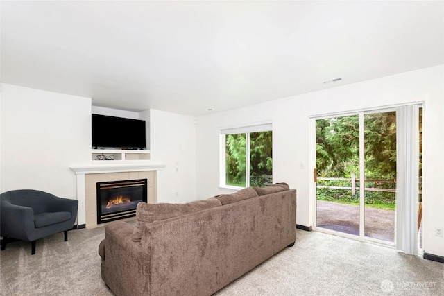 living room featuring light colored carpet, a fireplace, and visible vents
