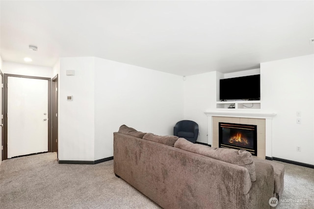 carpeted living room with a tiled fireplace and baseboards