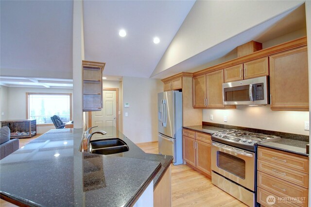 kitchen featuring recessed lighting, dark stone countertops, a sink, light wood-style floors, and appliances with stainless steel finishes