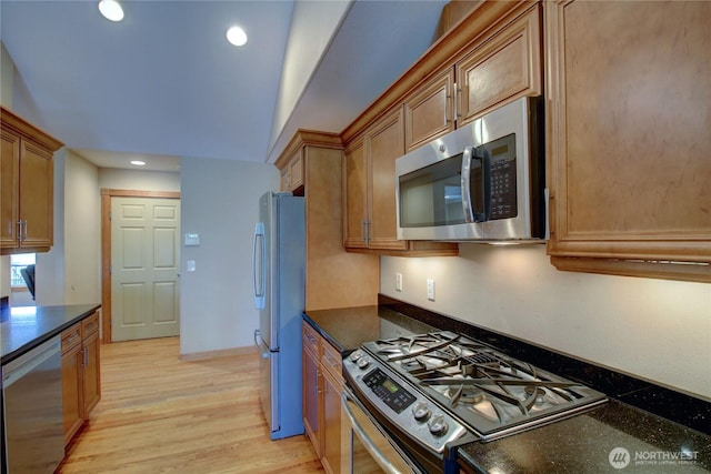 kitchen featuring dark stone countertops, recessed lighting, light wood-style floors, brown cabinetry, and appliances with stainless steel finishes