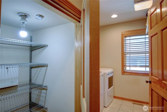 laundry area featuring washer and dryer, baseboards, light tile patterned flooring, and laundry area