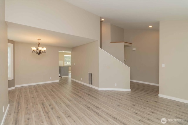 unfurnished room featuring baseboards, visible vents, light wood-style flooring, and a chandelier
