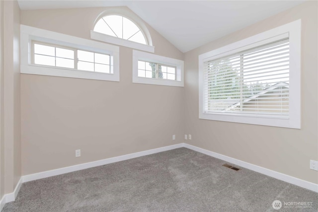 empty room with baseboards, visible vents, carpet floors, and vaulted ceiling