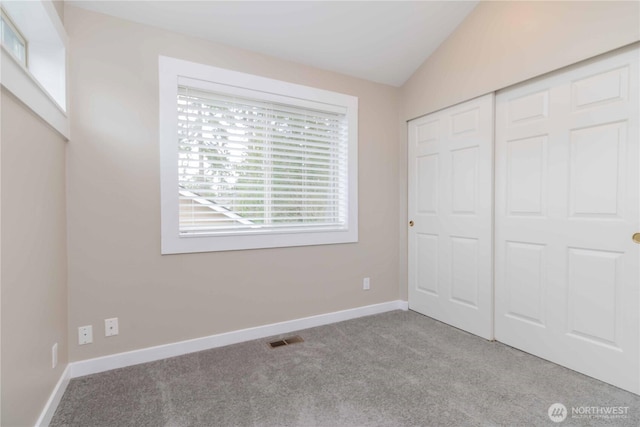 unfurnished bedroom featuring a closet, lofted ceiling, baseboards, visible vents, and carpet