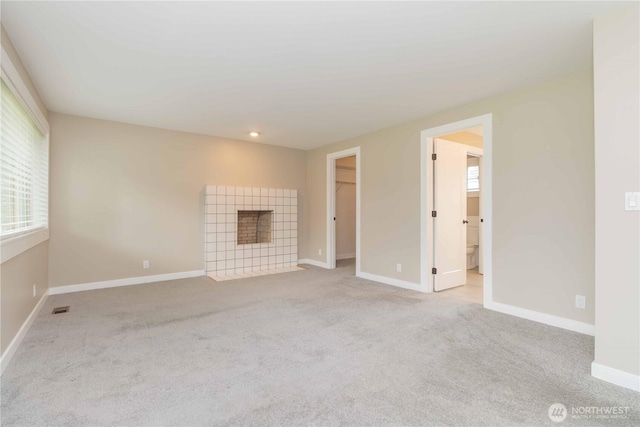 unfurnished living room featuring carpet floors, baseboards, a fireplace, and visible vents
