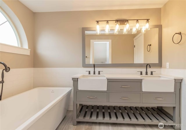 full bathroom featuring a soaking tub, double vanity, and a sink